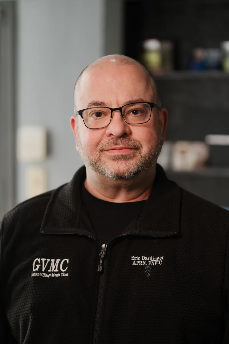 Eric Dardinger in a black GVMC fleece embroidered APRN, FNP-C, photographed inside the clinic.